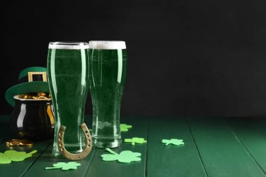 St. Patrick 'in gündüz partisi. Yeşil bira, leprikon şapka, bir küp altın, at nalı ve ahşap masa üzerindeki dekoratif yonca yaprakları. Metin için boşluk