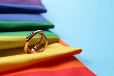Gökkuşağı LGBT bayrağı ve açık mavi arka planda alyanslar, yakın plan. Metin için boşluk
