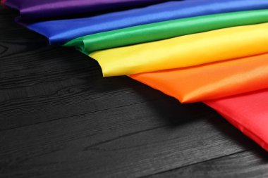 Siyah ahşap arka planda gökkuşağı LGBT bayrağı, yakın plan. Metin için boşluk