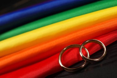 Gökkuşağı LGBT bayrağı ve siyah ahşap arka planda alyanslar