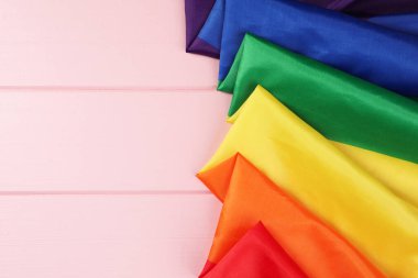 Gökkuşağı LGBT bayrağı pembe ahşap masada, üst manzara. Metin için boşluk