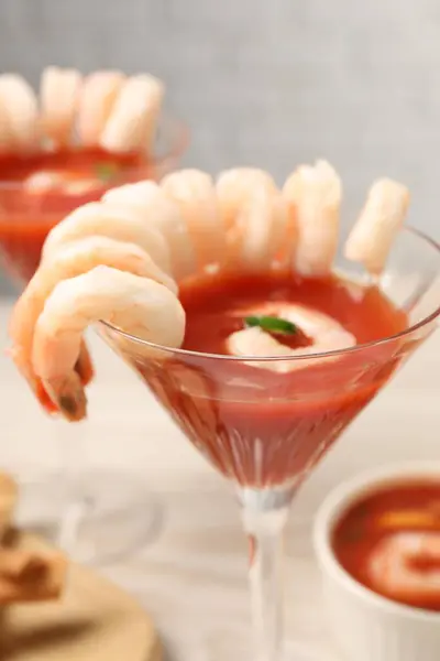 Tasty shrimp cocktail with sauce in glasses on table, closeup