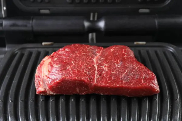 Cooking fresh beef cut on electric grill, closeup