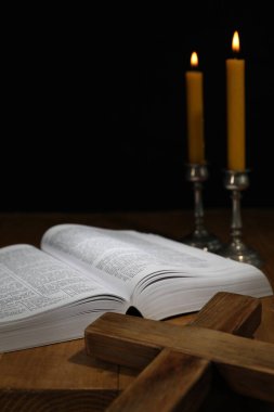 İncil, haç ve kilise mumları ahşap masada.