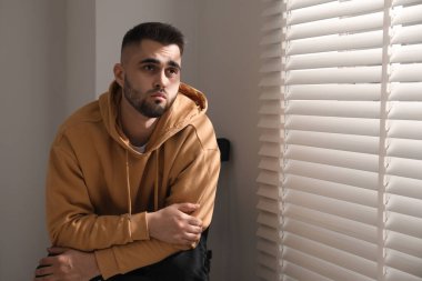 Pencerenin yanındaki sandalyede oturan üzgün adam