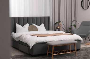 Şık bir yatak odası. Büyük yatak odası, kanepe, lamba ve çiçek.