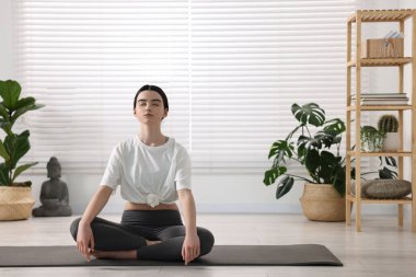 Yoga stüdyosunda minder üzerinde meditasyon yapan güzel kız.