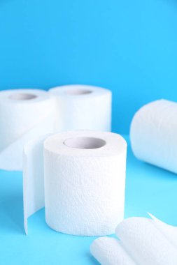 Açık mavi arkaplanda yumuşak tuvalet kağıdı yuvarlanıyor