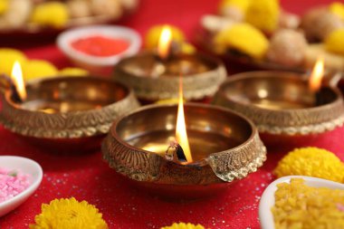 Diwali kutlaması. Diya lambaları ve kasımpatı çiçekleri parlak kırmızı masada, yakın plan
