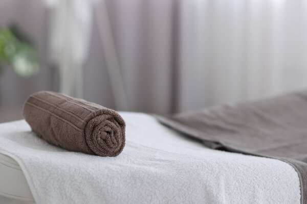 Rolled towel on massage table in spa center, closeup