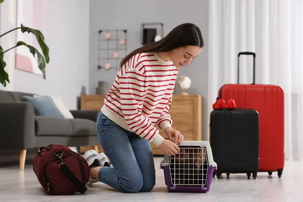 Smiling woman closing carrier with her pet before travelling indoors