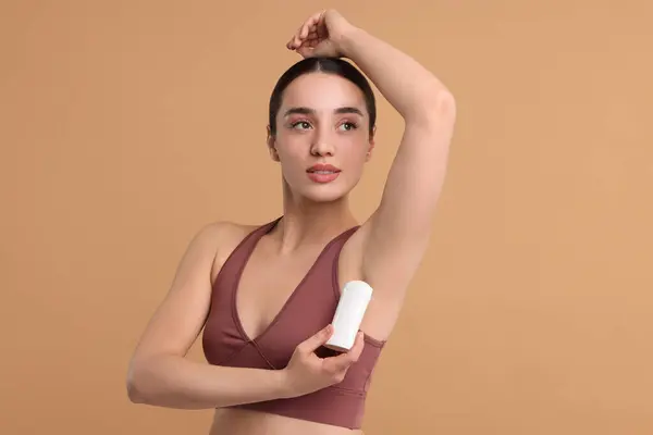 Piękna Kobieta Stosująca Dezodorant Beżowym Tle — Zdjęcie stockowe