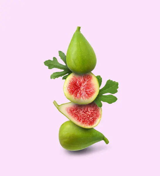 Stacked green figs and leaves on pale pink background