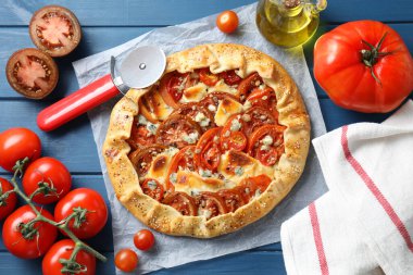 Mavi ahşap masa üzerinde domates ve peynirli (Caprese galette) leziz galette düz bir bileşim yatıyordu