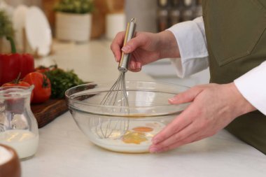 Kapalı mekânda yumurta çırpan bir kadın.