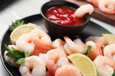 Kokteyl soslu kaynamış karides, maydanoz ve limon açık gri masada, yakın plan.