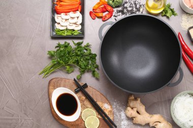 Wok, çubuklar ve gri desenli masa üzerinde farklı ürünler, düz yatak. Metin için boşluk