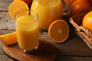 Lezzetli taze portakallar ve meyve suyu ahşap masada, yakın plan.