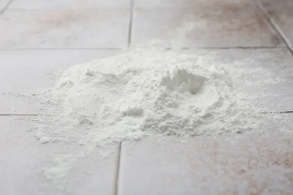 Pile of baking powder on light tiled table, closeup