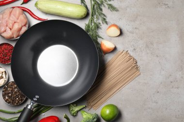 Gri masadaki ham malzemelerle çevrili boş demir tava, düz. Metin için boşluk