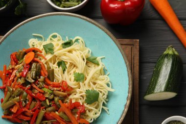 Vejetaryen yemeği. Lezzetli makarna ve taze sebzeler, koyu ahşap masa, düz uzanmış