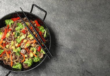 Kızarmış erişteyi mantarla karıştır ve tavada sebzeler, gri masa, üst manzara. Metin için boşluk