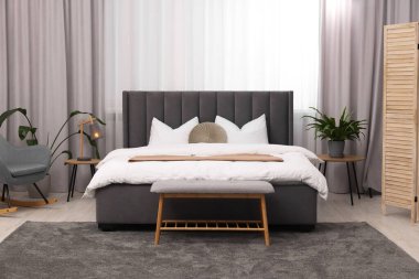 Şık bir yatak odası. Büyük yatak odası, kanepe, lamba ve çiçek.