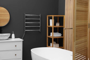 Isıtılmış havlu parmaklıkları ve modern mobilyaları olan şık bir banyo.