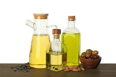 Sebze yağları. Ahşap masadaki farklı yağlar ve malzemeler beyaz arka plana karşıdır.