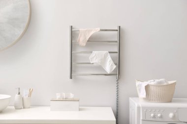 Banyodaki beyaz duvarda iç çamaşırı olan ısıtmalı havlu rayı.