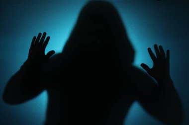 Mavi arka planda camın arkasındaki hayalet silueti