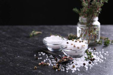 Taze kekikli tuz ve koyu gri desenli masada biber, yakın plan. Metin için boşluk