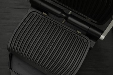 Siyah ahşap masada elektrikli ızgara, üst manzara. Yemek pişirme aygıtı