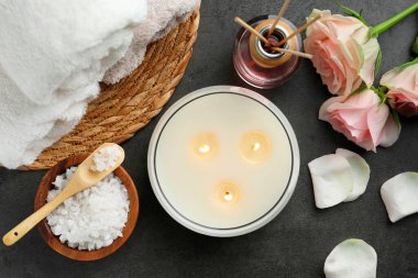 Gri masa üzerinde farklı spa ürünleri ve gül çiçekleri içeren düz bir kompozisyon.