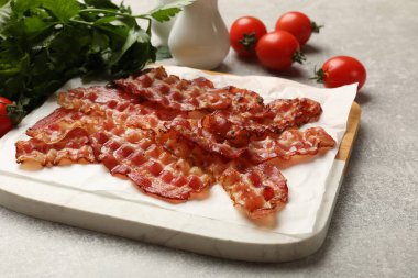 Kızarmış domuz pastırması, domates ve maydanoz. Gri desenli masa, yakın plan.