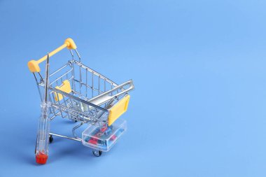 Açık mavi arka planda inşaat aletleri olan küçük bir alışveriş arabası. Metin için boşluk