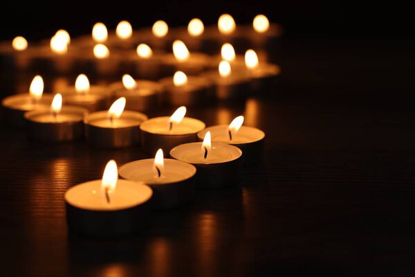 Burning candles on dark surface, closeup. Space for text
