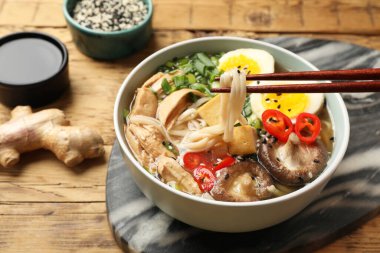 Ahşap masada çubuklarla lezzetli ramen yemek, yakın plan. Erişte çorbası.