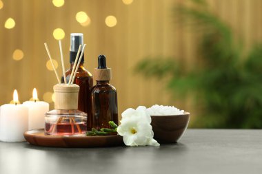 Farklı spa ürünleri içeren kompozisyon ve açık gri masa üzerinde mum yakma, metin için boşluk