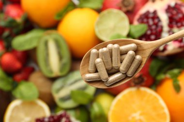 Kaşıkta vitamin hapları, taze meyveler, üst manzara. Metin için boşluk
