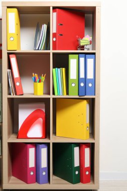 İçerideki raf ünitesinde renkli klasör ofis dizinleri ve kırtasiye malzemeleri