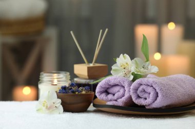 Bulanık arka planda beyaz havluyla farklı spa ürünleri ve çiçeklerle güzel bir kompozisyon