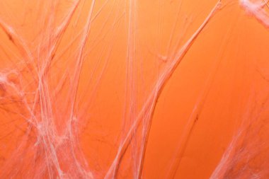 Turuncu arka planda asılı ürkütücü beyaz örümcek ağı