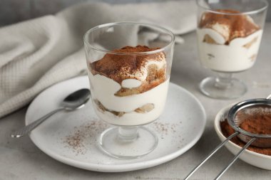 Bardakta nefis tiramisu ve ışık masasında kakao tozuyla elek.