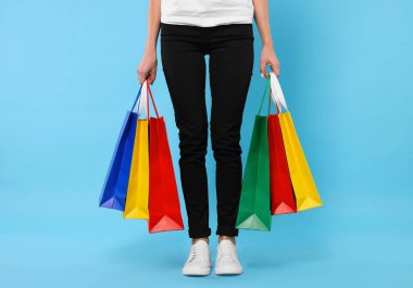 Açık mavi arka planda alışveriş torbaları olan kadın, yakın plan.