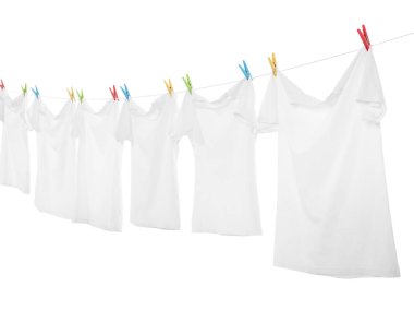 Çamaşır ipinde kuruyan birçok tişört beyaza izole edilmiş.