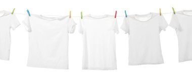 Çamaşır ipinde kuruyan birçok tişört beyaza izole edilmiş.