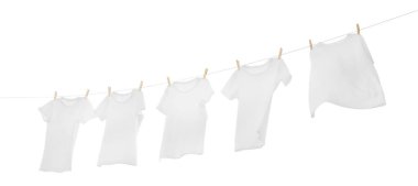 Çamaşır ipinde kuruyan birçok tişört beyaza izole edilmiş.