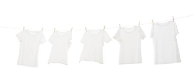 Çamaşır ipinde kuruyan birçok tişört beyaza izole edilmiş.