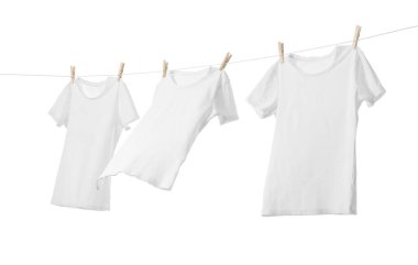 Çamaşır ipinde kuruyan birçok tişört beyaza izole edilmiş.